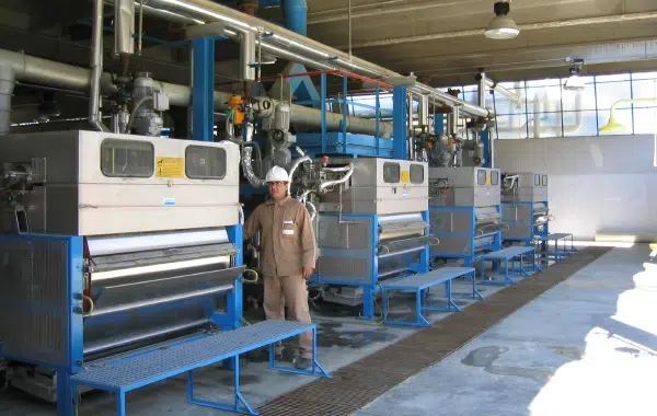 Operaio in fabbrica tra macchinari industriali.